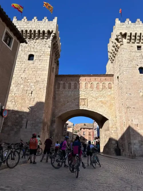 Grupo de ciclistas bajo la Puerta Baja de Daroca durante el viaje por la Vía Verde Santander-Mediterráneo